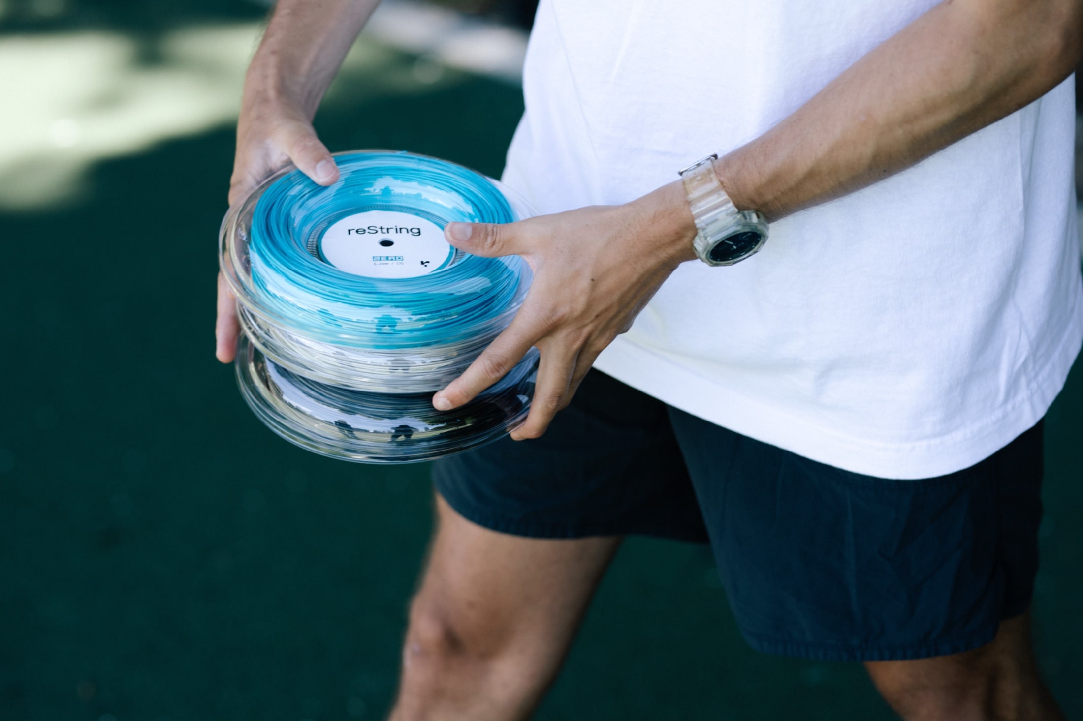 Reels of reString racket string held in hand on court