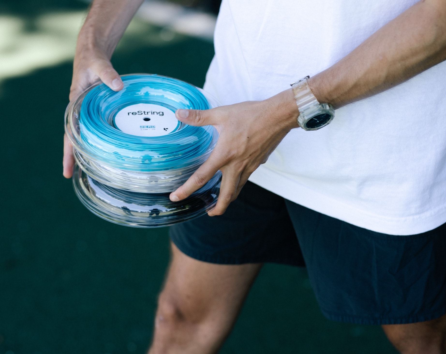 Reels of reString racket string held in hand on court